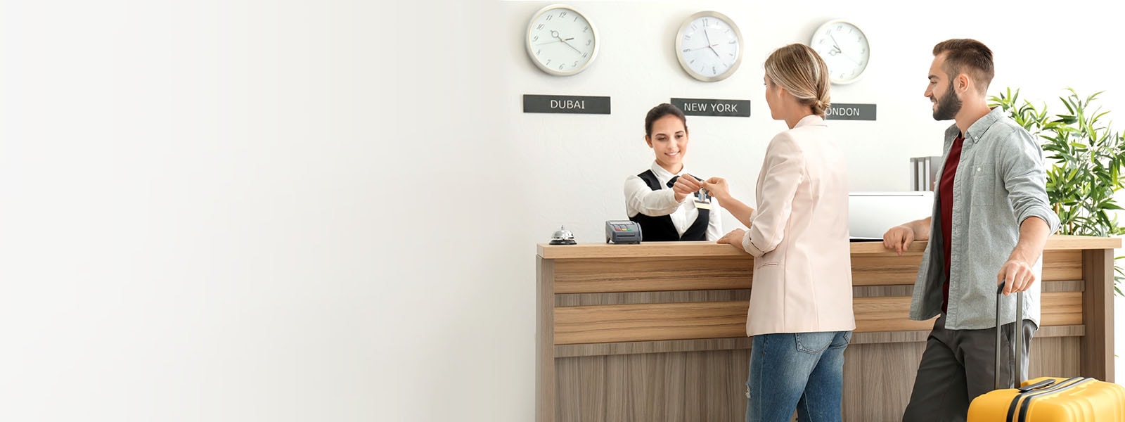 Slika para koji se prijavljuje na recepciji u lobiju hotela.