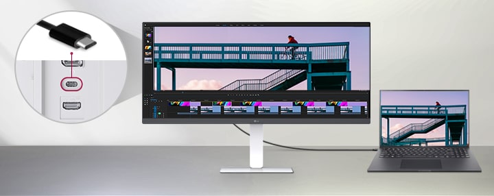 Кабель USB Type-C, подключающий ноутбук к сверхширокому монитору LG, с крупным планом, показывающим порт USB-C на задней панели монитора, и программой редактирования видео, работающей на обоих экранах.