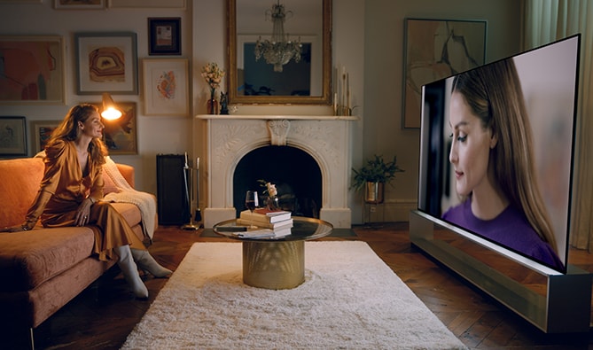 Оливия Палермо смотрит на себя на телевизоре LG SIGNATURE OLED 8K в гостиной.