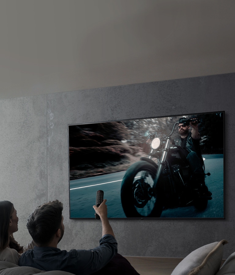 Na obrázku je pár, ktory na televízore LG s rozlí?ením UHD sleduje program.