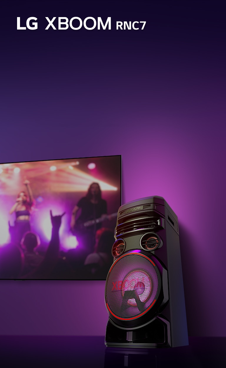 Poh?ad z nízkeho uhla na pravú stranu reproduktora LG XBOOM RNC7 na fialovom pozadí. Svetlo XBOOM je tie? fialové. A na televíznej obrazovke sa zobrazuje scéna z koncertu.