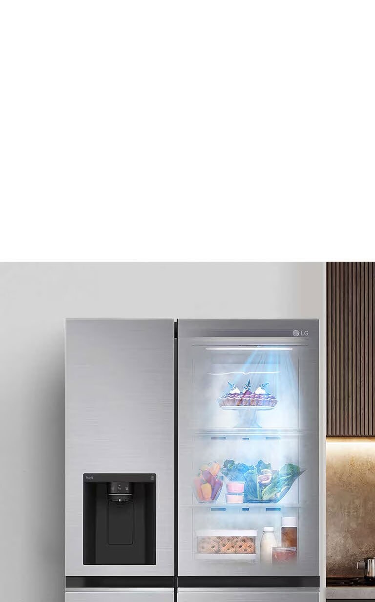 Poh?ad spredu na chladni?ku so zapnutym svetlom vo vnútri. Obsah chladni?ky vidie? cez prieh?adny otvor InstaView v dverách. Modré svetelné lú?e funkcie DoorCooling vy?arujú nadol a prechádzajú cez obsah chladni?ky.