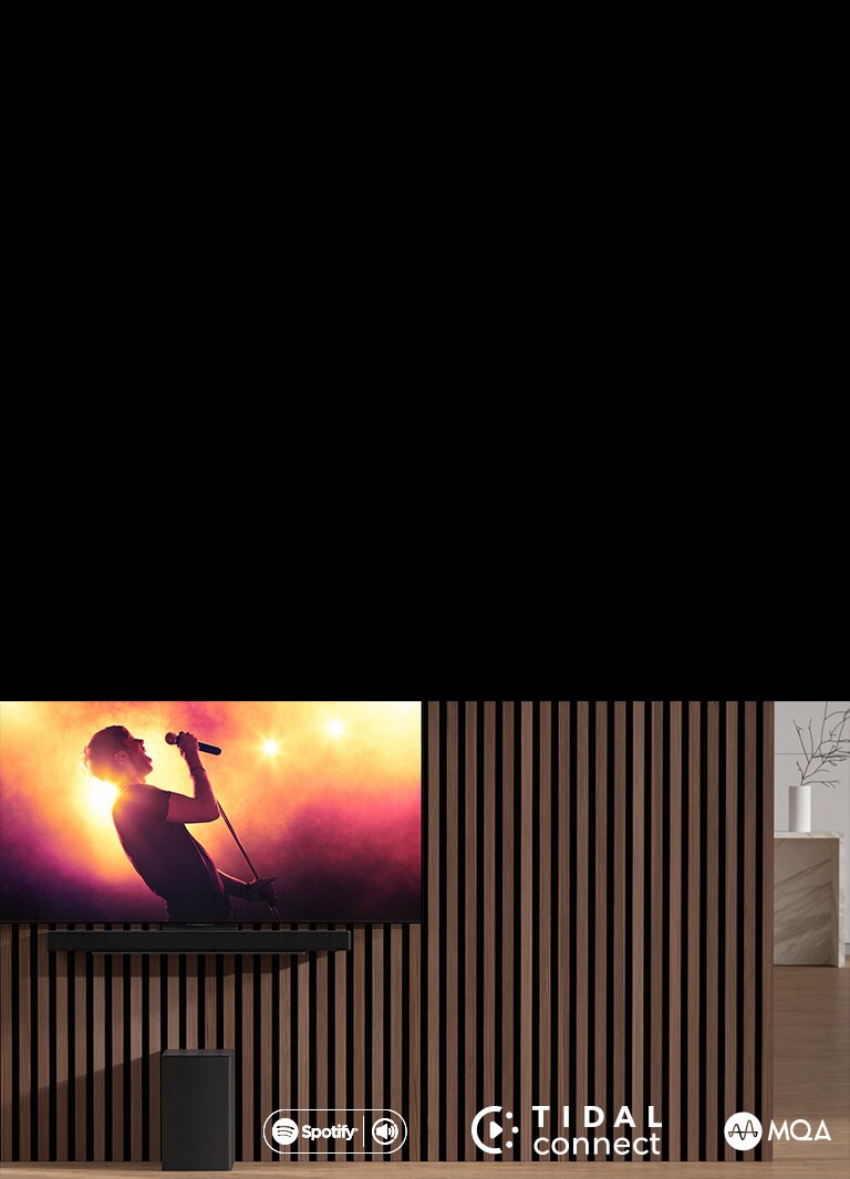 Model LG OLED C je umiestneny na stene. Pod ním je umiestneny zvukovy panel LG SC9S prostredníctvom exkluzívnej konzoly. Ni??ie sa nachádza subwoofer. Na obrazovke televízora sa zobrazuje scéna z koncertu.