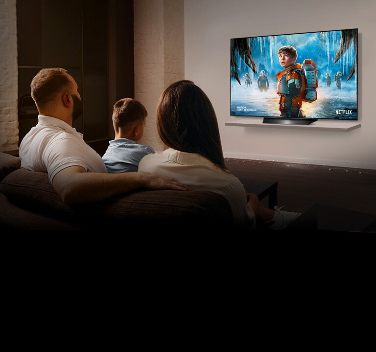 Pár sediaci na pohovke v obyvacej izbe sleduje na televízore romanticky film