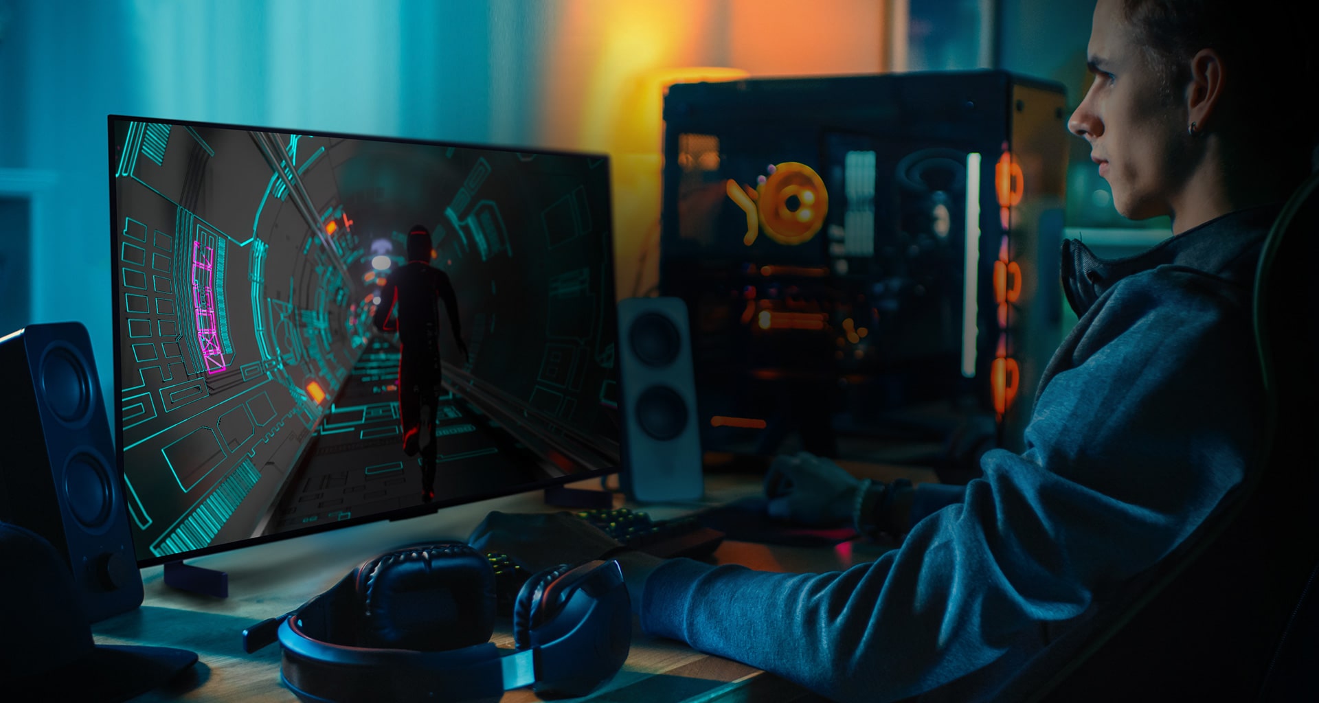 Mlady mu? sedí za pracovnym stolom a hrá sci-fi hru na malom OLED televízore LG