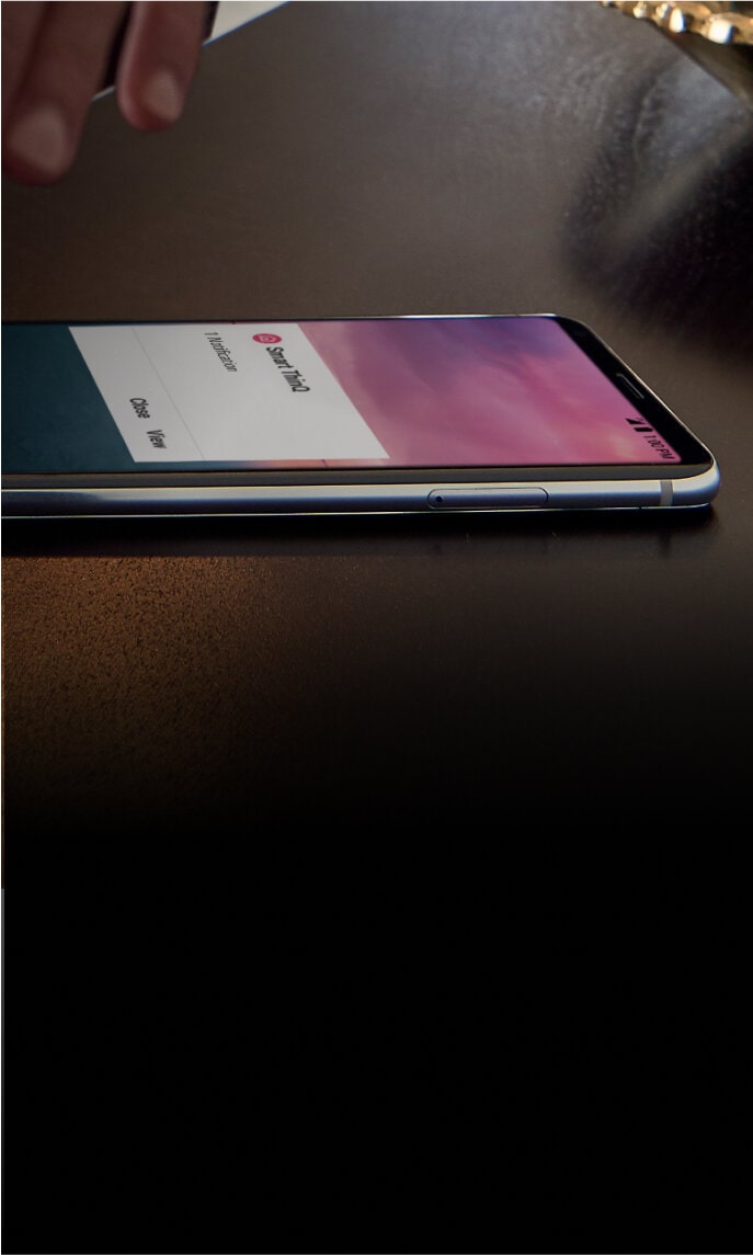 A smartphone displaying the LG ThinQ app on a dark surface next to a key fob and a bowl, promoting the reliability of LG appliances with ThinQ Care? technology. Badges showing 'Most Reliable' and '2 Year Warranty' are also visible.
