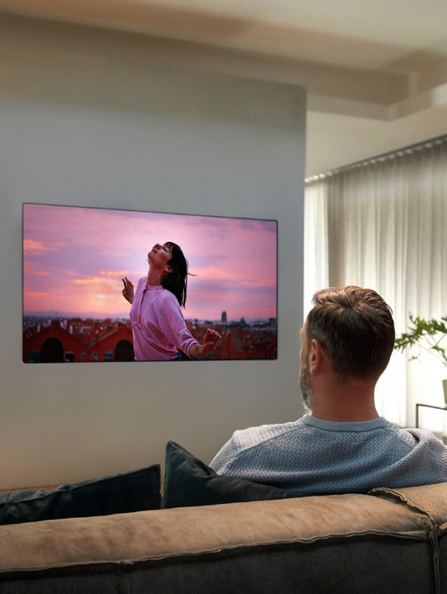 juftlik divanda o?tirgancha mehmonxonadagi televizorni tomosha qilmoqda.