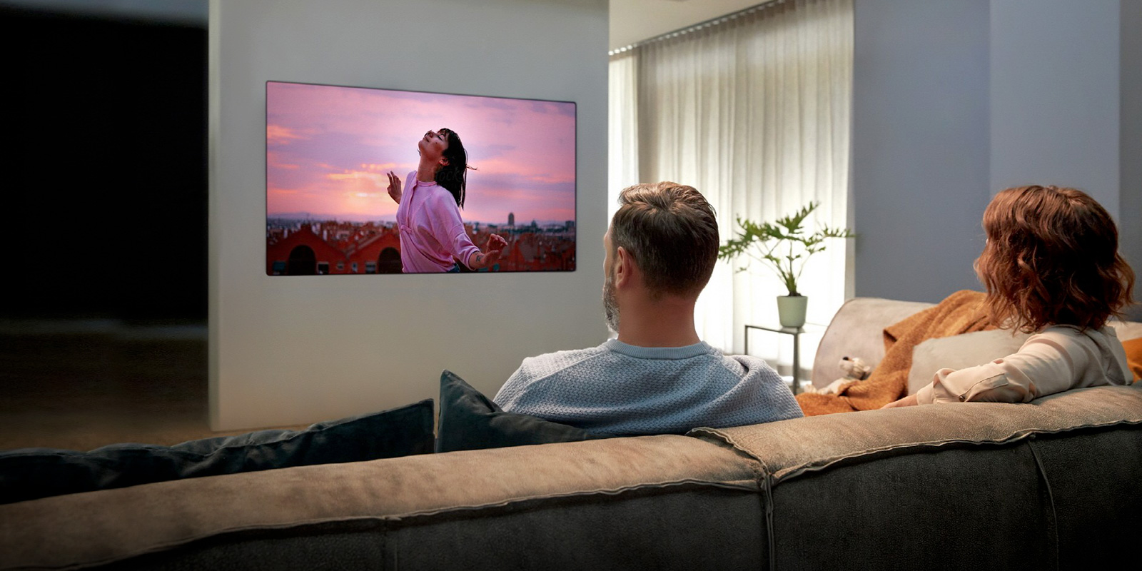 juftlik divanda o?tirgancha mehmonxonadagi televizorni tomosha qilmoqda.